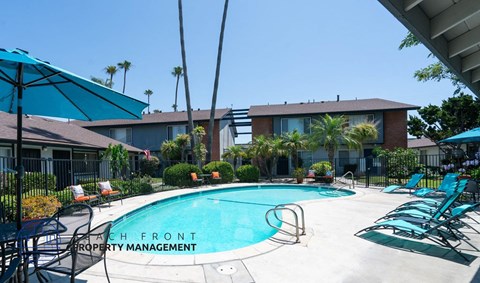 a swimming pool with chairs and umbrellas in front of a building